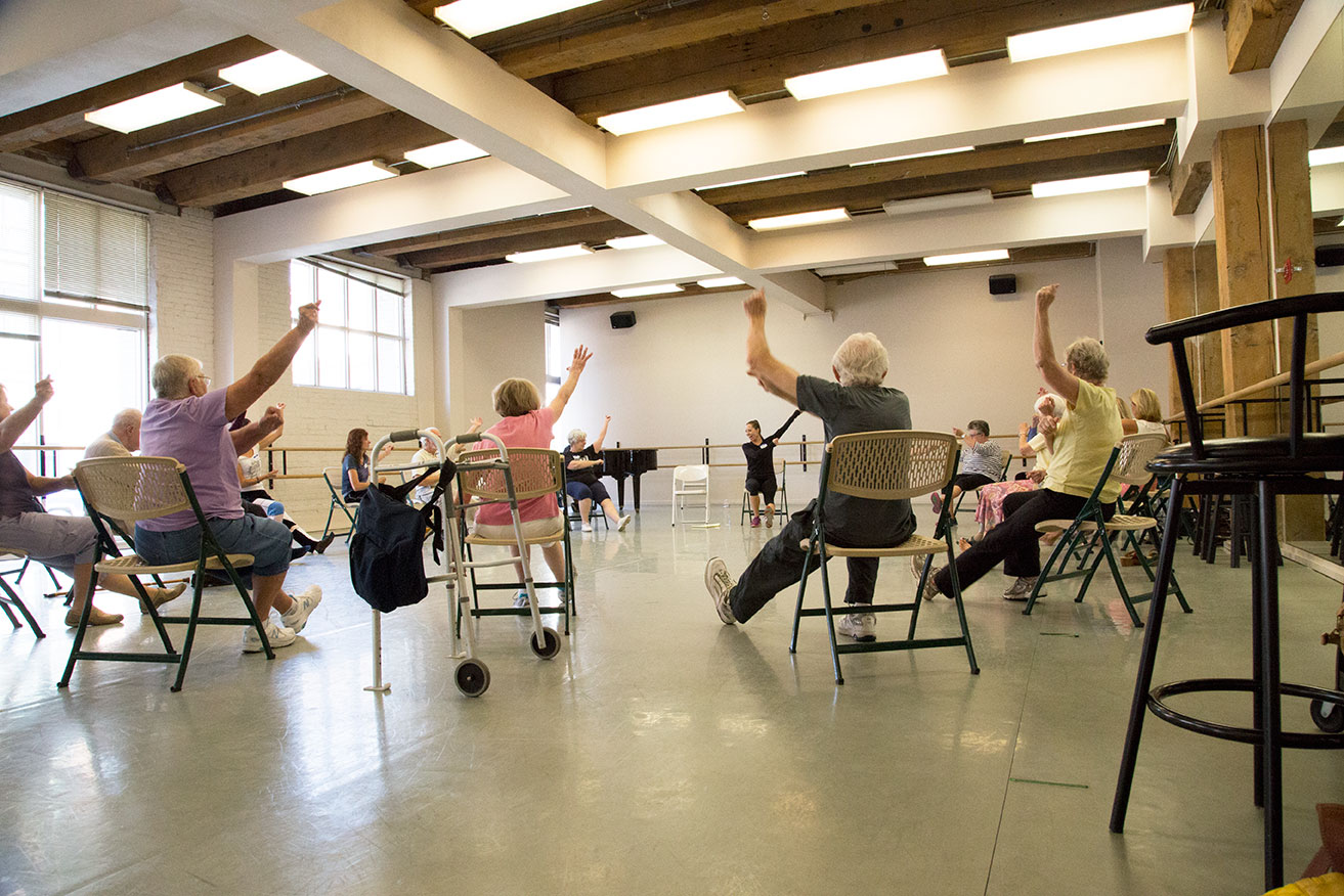 Seated dancers raising their arms with energy